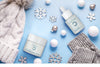 Noche products surrounded by white snowflakes, small snowballs, and gray accessories on a sky blue background.